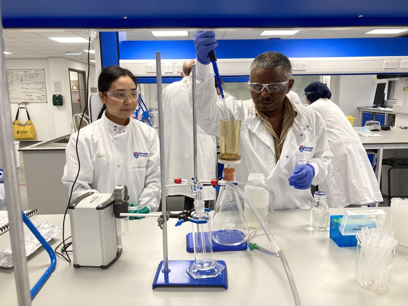 Two hub colleagues carry out water sample testing using equipment on a laboratory bench